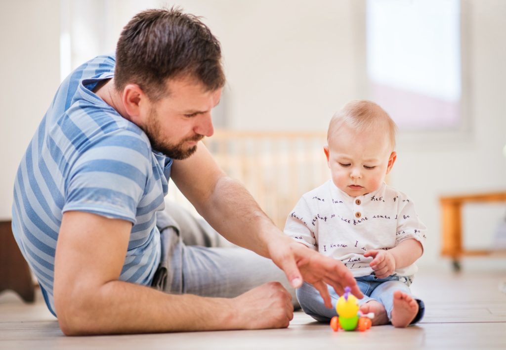 Young father playing with a baby son at home.